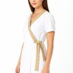 Elegancki biały uniform kosmetyczny dla kobiet z beżową lamówką i wiązaniem, idealny dla kosmetologów i personelu medycznego.